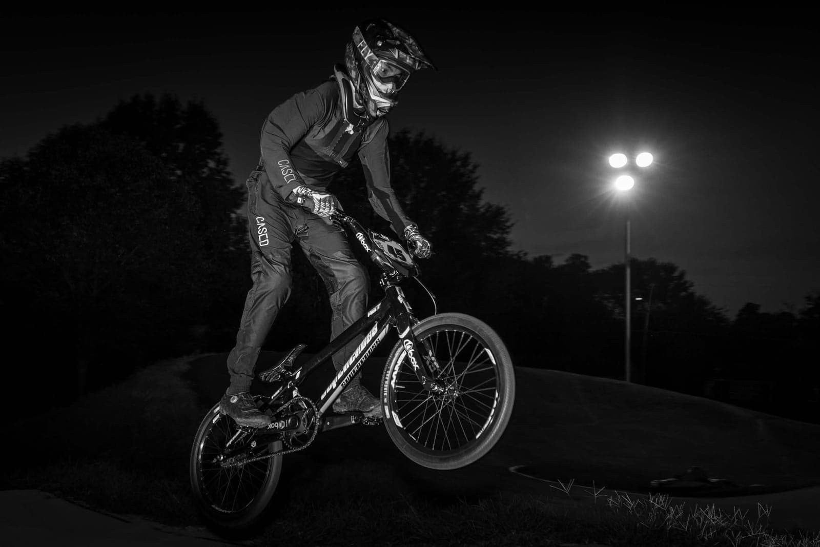 Liam G Adams doing a manual on a BMX bike at night, 2025